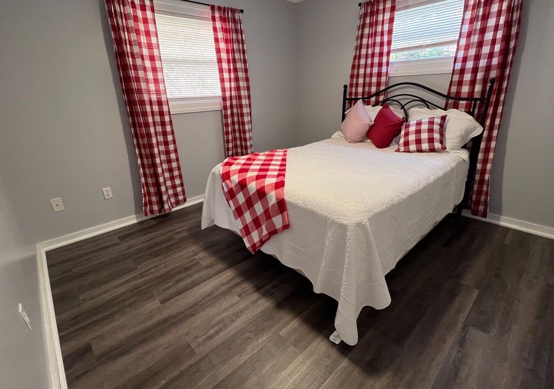 Cozy bedroom with charming red gingham accents creates your perfect country retreat. Crisp linens and natural light invite peaceful rest.