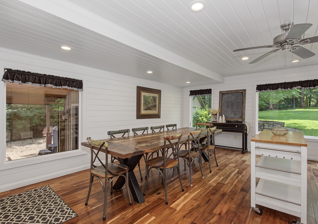 Gather your group around this inviting farmhouse-style dining table for memorable meals together. Natural light floods the space, and you can enjoy views of the lush green lawn through large windows.