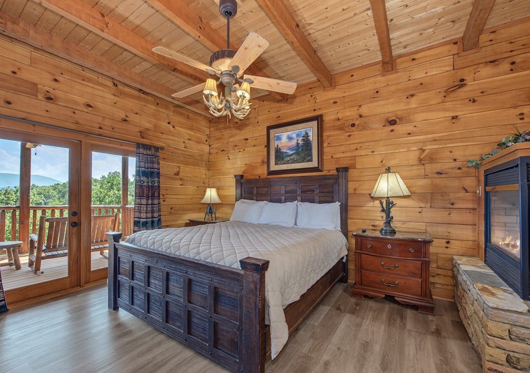 Step into your cozy mountain bedroom featuring a handsome king bed, warm wood-beamed ceiling, and private deck access where you can enjoy stunning views over morning coffee or evening relaxation.