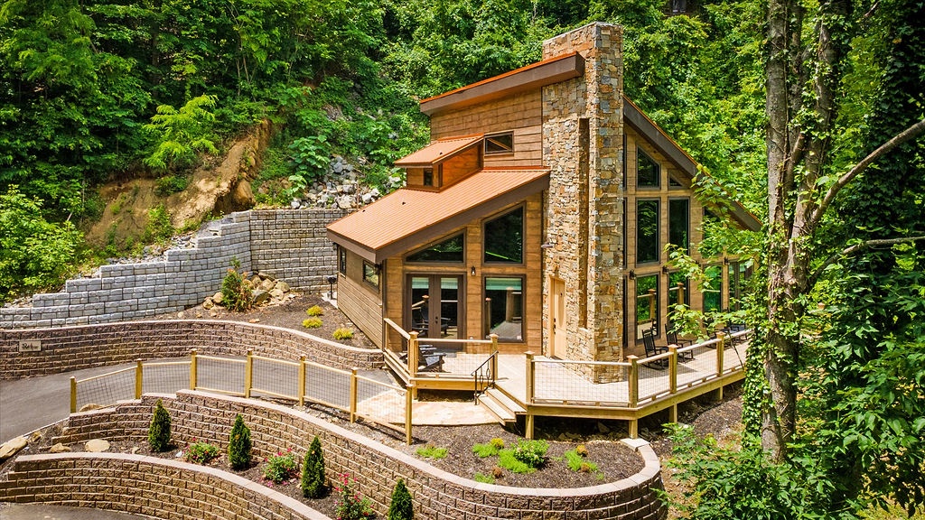 This stunning modern cabin offers a peaceful forest retreat with floor-to-ceiling windows, a stone chimney, and expansive outdoor deck—perfect for reconnecting with nature.