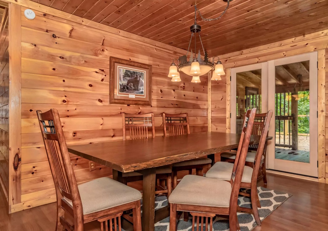 Gather around your rustic dining table where warm wood surrounds you and natural light streams through French doors to the deck.