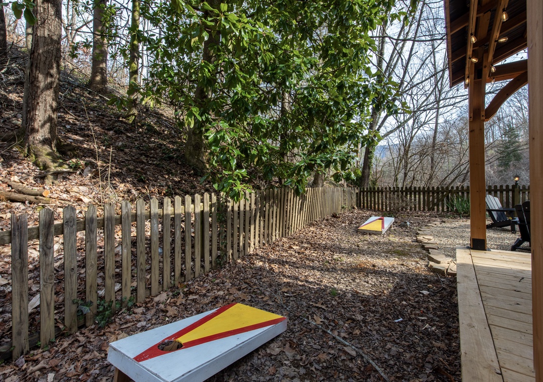 Your private cornhole court awaits under the canopy of towering trees, where friendly competition meets forest tranquility on this leaf-strewn playing field.