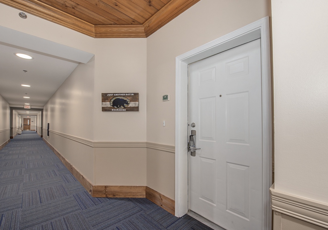 Welcoming hallway with rustic wood ceiling accents and modern carpeting leading to your comfortable accommodation.