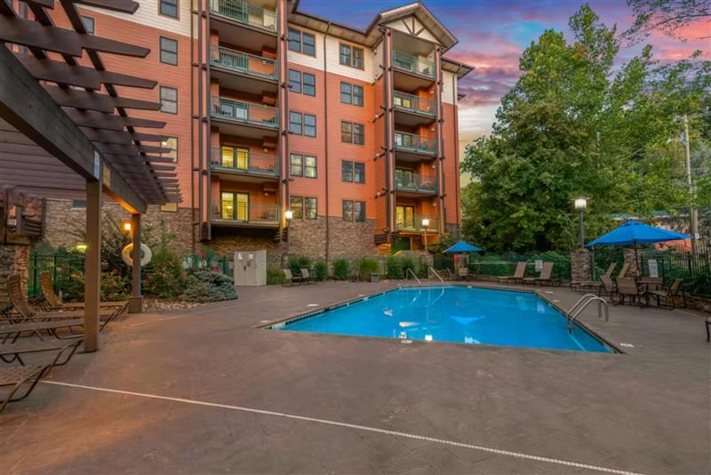 A sparkling pool awaits beneath the colorful evening sky at this well-appointed mountain resort.