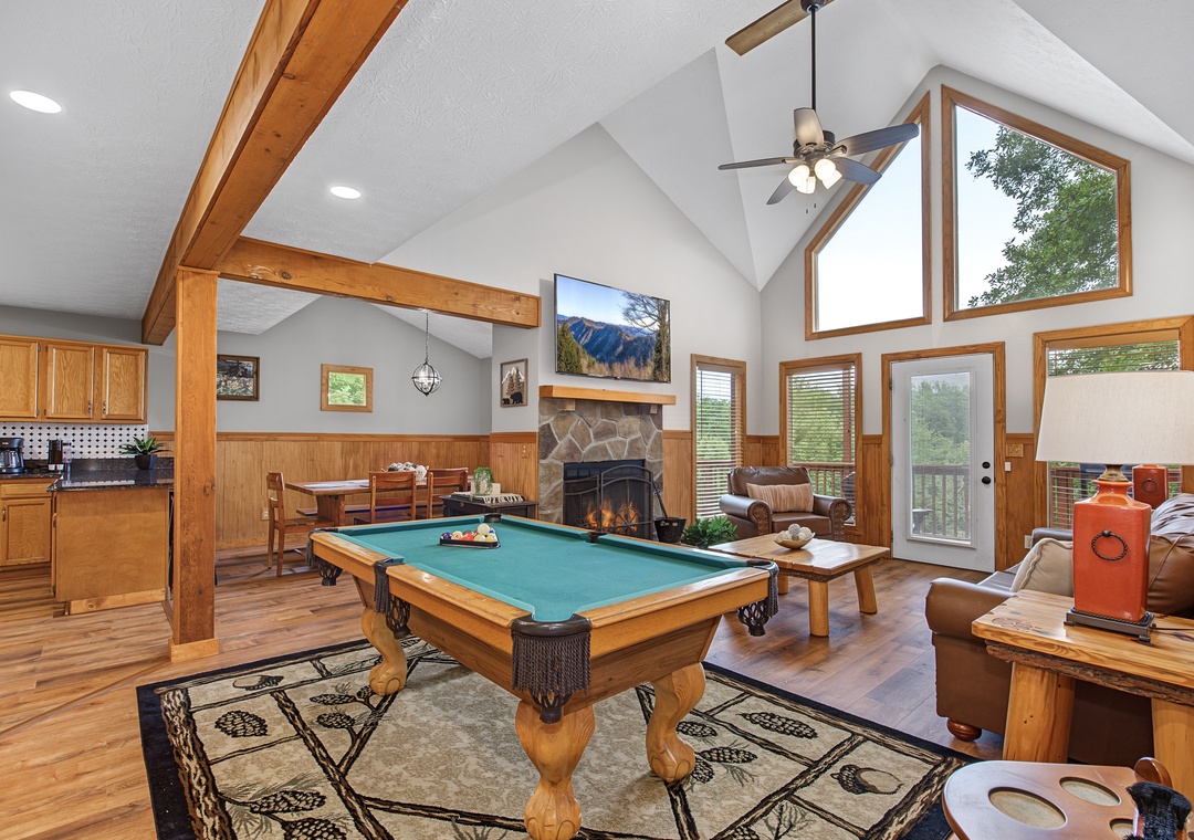 Relax in your spacious great room where soaring vaulted ceilings and warm wood beams create an inviting mountain retreat. Enjoy games at the billiard table, cozy up by the fireplace, and savor views of lush trees through large windows.