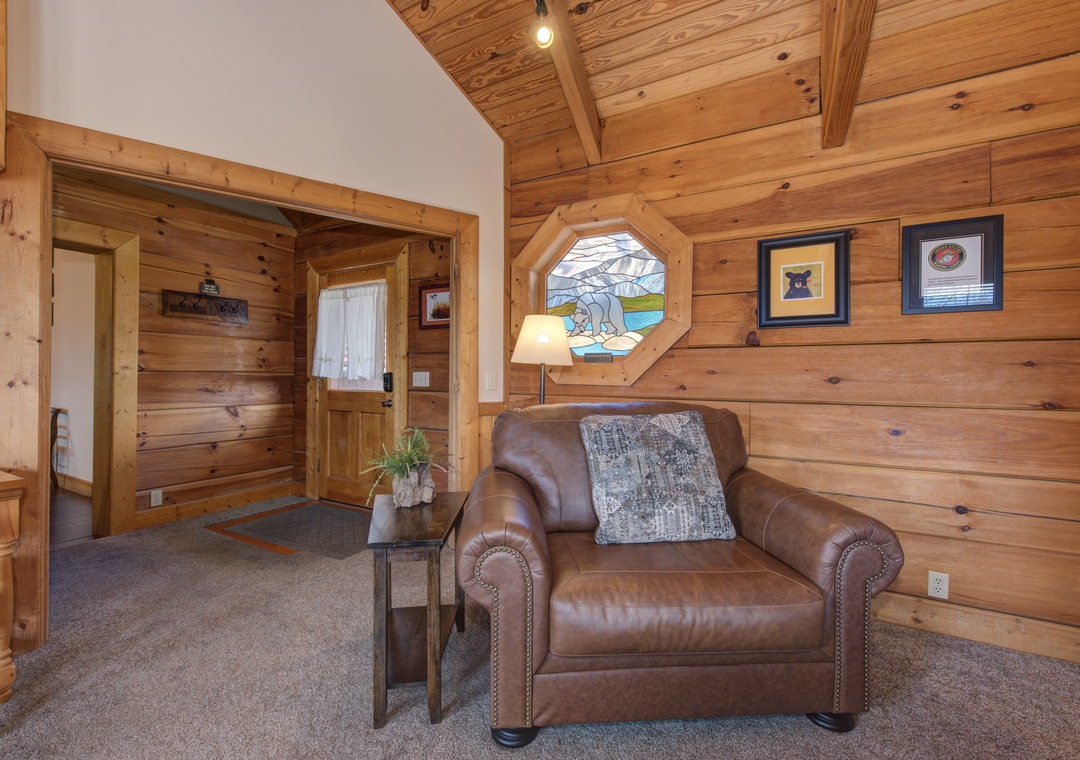 Sink into this cozy leather armchair surrounded by warm wood walls and peaceful mountain artwork—your perfect reading nook awaits.