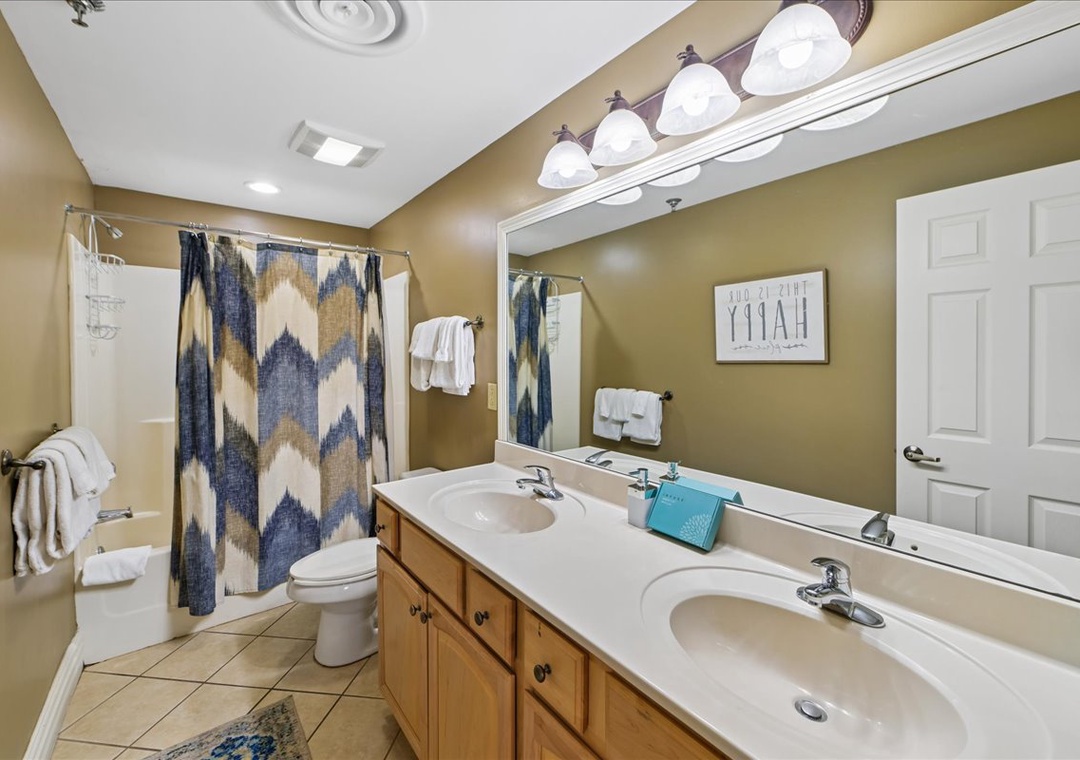 Freshen up in your spacious bathroom with dual sinks, warm lighting, and cheerful blue-gold accents that make morning routines feel luxurious.