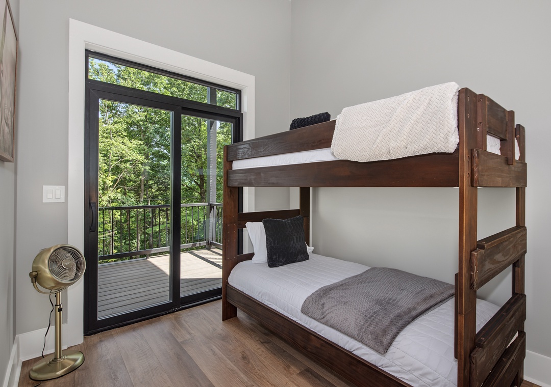 Wake up to peaceful green treetops framed by your private balcony—this cozy bunk room invites you to relax and reconnect with nature right outside.