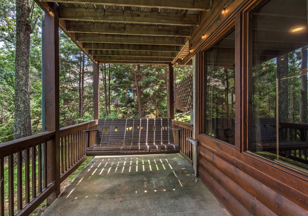 Swing gently in your private covered porch, surrounded by towering pines and filtered sunlight, the perfect spot to unwind with morning coffee or an evening book.