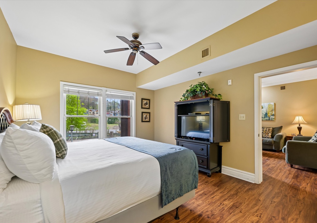 Unwind in your spacious bedroom with cozy linens, ceiling fan, and entertainment center for ultimate relaxation after exploring.