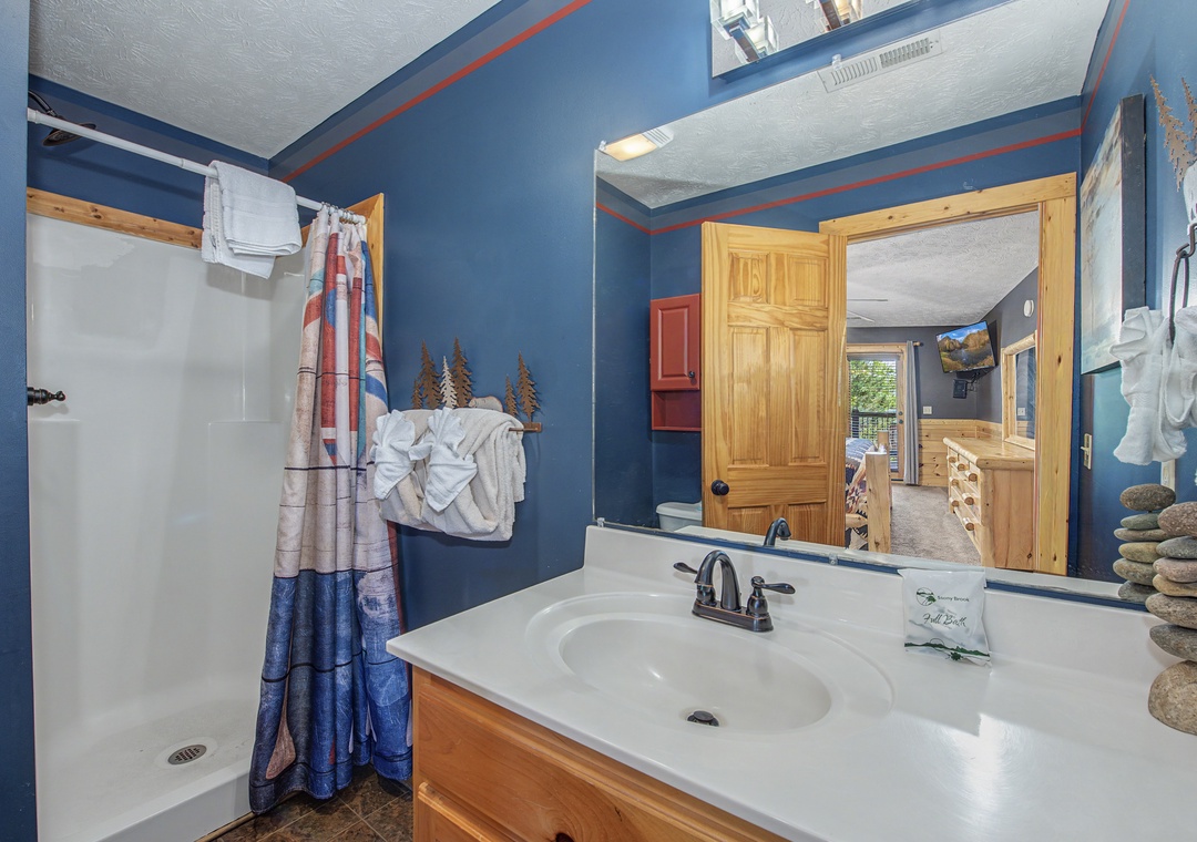 Your rustic bathroom features warm blue walls and natural wood accents, creating a cozy mountain cabin atmosphere for your retreat.