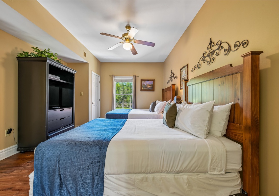 Rest peacefully in your cozy bedroom with comfortable beds, rustic charm, and modern amenities like TV and ceiling fan.