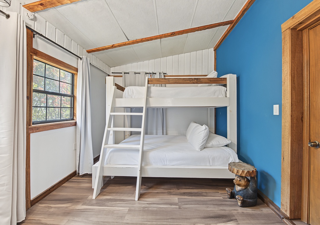 Gather the kids for cozy nights in this cheerful bunk room, where rustic wood beams and a playful splash of blue create the perfect hideaway for memorable family moments.