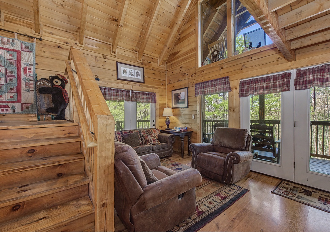 Relax in your cozy cabin living room with rustic wood beams, comfortable leather seating, and peaceful forest views through French doors.
