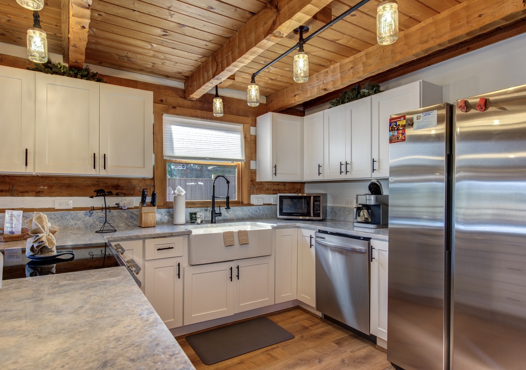 Cook your favorite meals in this rustic-modern kitchen with stainless steel appliances, granite counters, and warm wood beam ceiling.