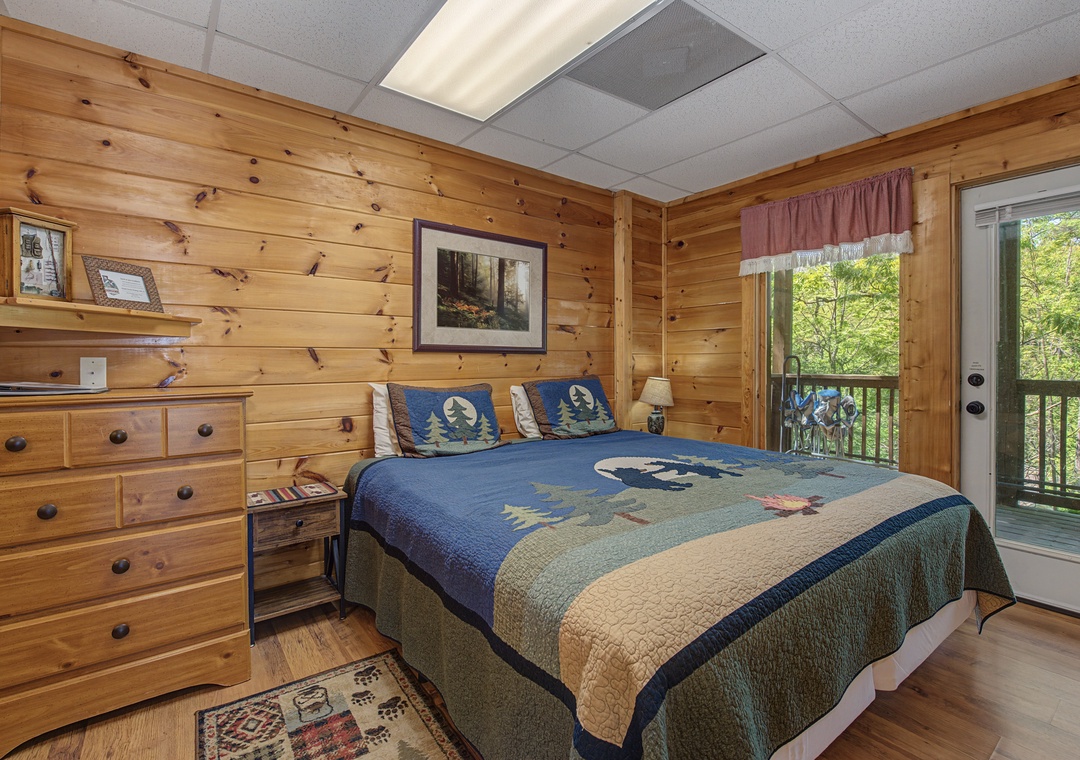 Wake up in this cozy cabin bedroom with warm wood walls, comfortable bedding, and your own private balcony overlooking the trees.