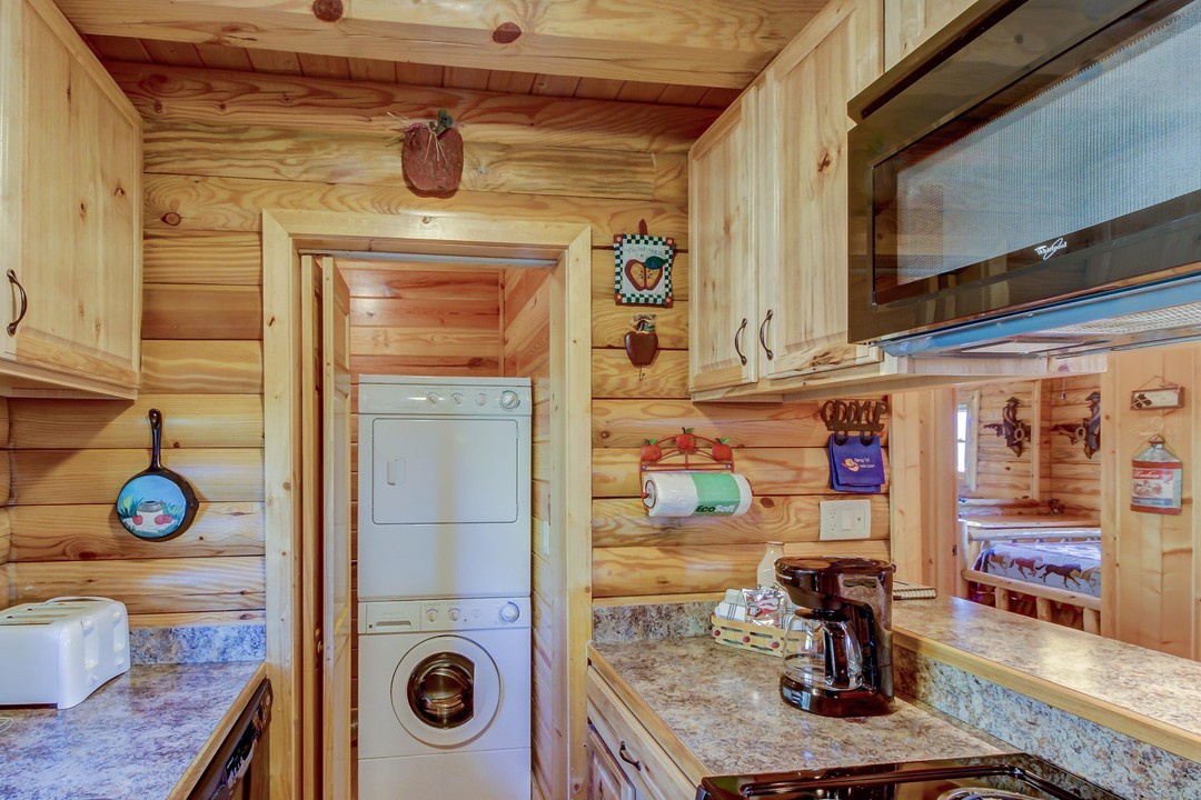Your cozy cabin kitchen comes fully equipped with everything you need—from the coffee maker ready for morning brews to the washer and dryer tucked conveniently nearby, all wrapped in warm, natural wood that makes you feel right at home.