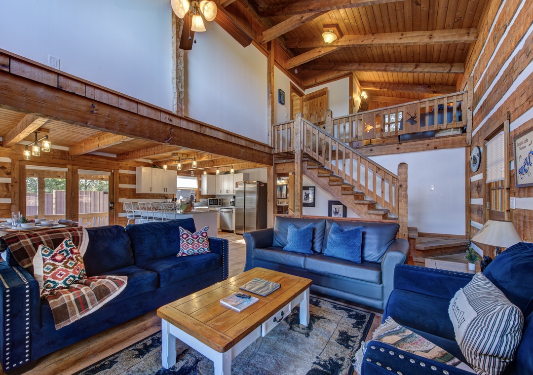 Gather in your spacious open-concept living room, where rich wood beams and cozy blue seating create the perfect mountain retreat atmosphere.