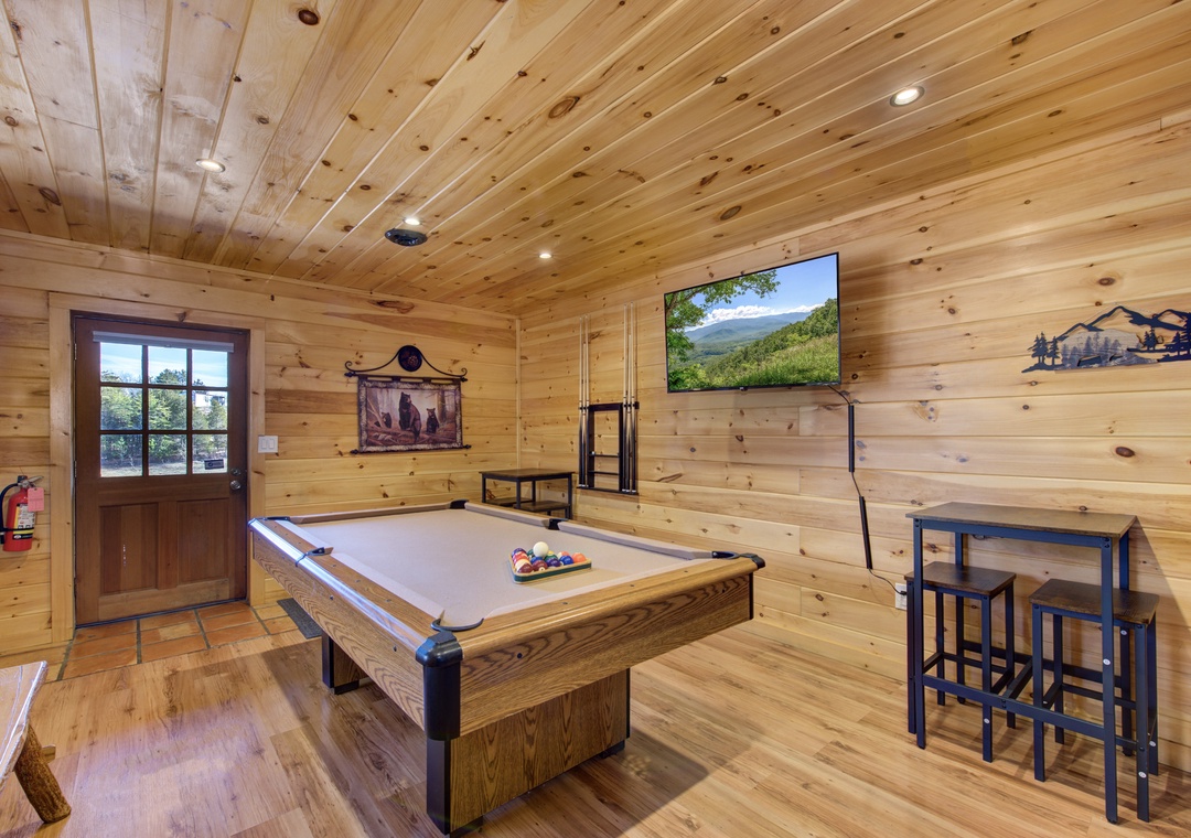 Challenge friends to pool while enjoying mountain views on the wall-mounted TV in this rustic game room.