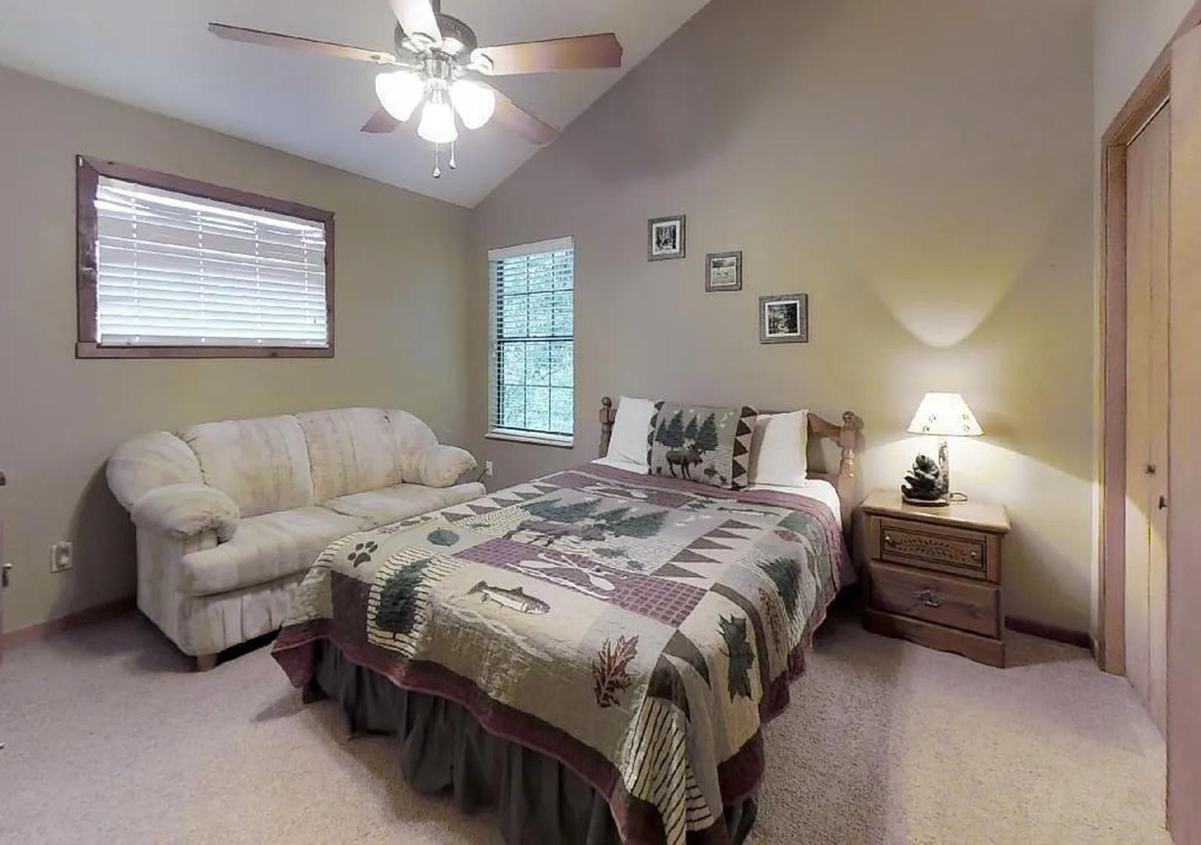 Your peaceful retreat features a plush queen bed adorned with rustic charm, complemented by a cozy loveseat for lounging and natural light filtering through soft window blinds.