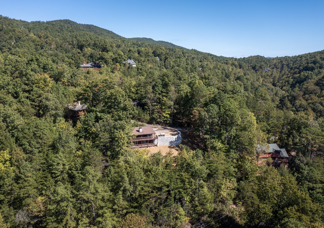 This mountain property sits nestled among lush forested hillsides, offering a secluded retreat surrounded by natural beauty and peaceful wilderness.