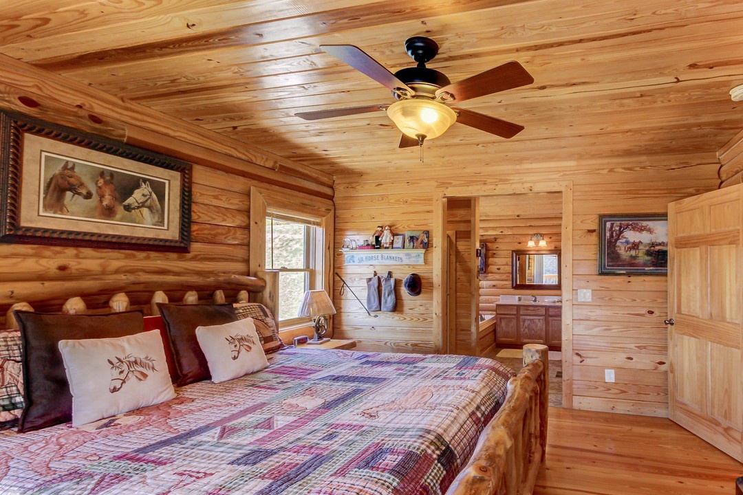 Step into your rustic retreat with warm pine walls, a handcrafted log bed dressed in cozy quilts, and charming equestrian touches that invite peaceful mountain dreams.