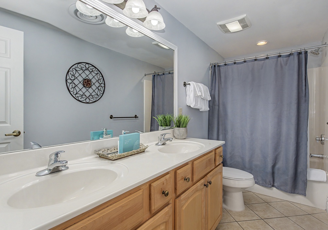 Freshen up in your spacious bathroom with dual sinks, warm wood vanity, and tub-shower combo perfect for relaxing after your adventures.