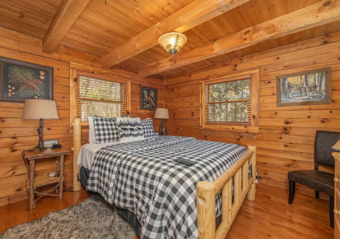Nestle into your rustic cabin bedroom, where warm pine walls, charming buffalo-check bedding, and soft bedside lighting create the perfect woodland retreat for a restful night's sleep.