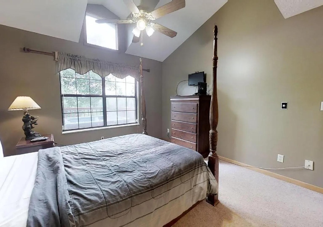 Unwind in your private bedroom featuring a plush four-poster bed, vaulted ceilings, and natural light streaming through large windows—your serene retreat awaits.