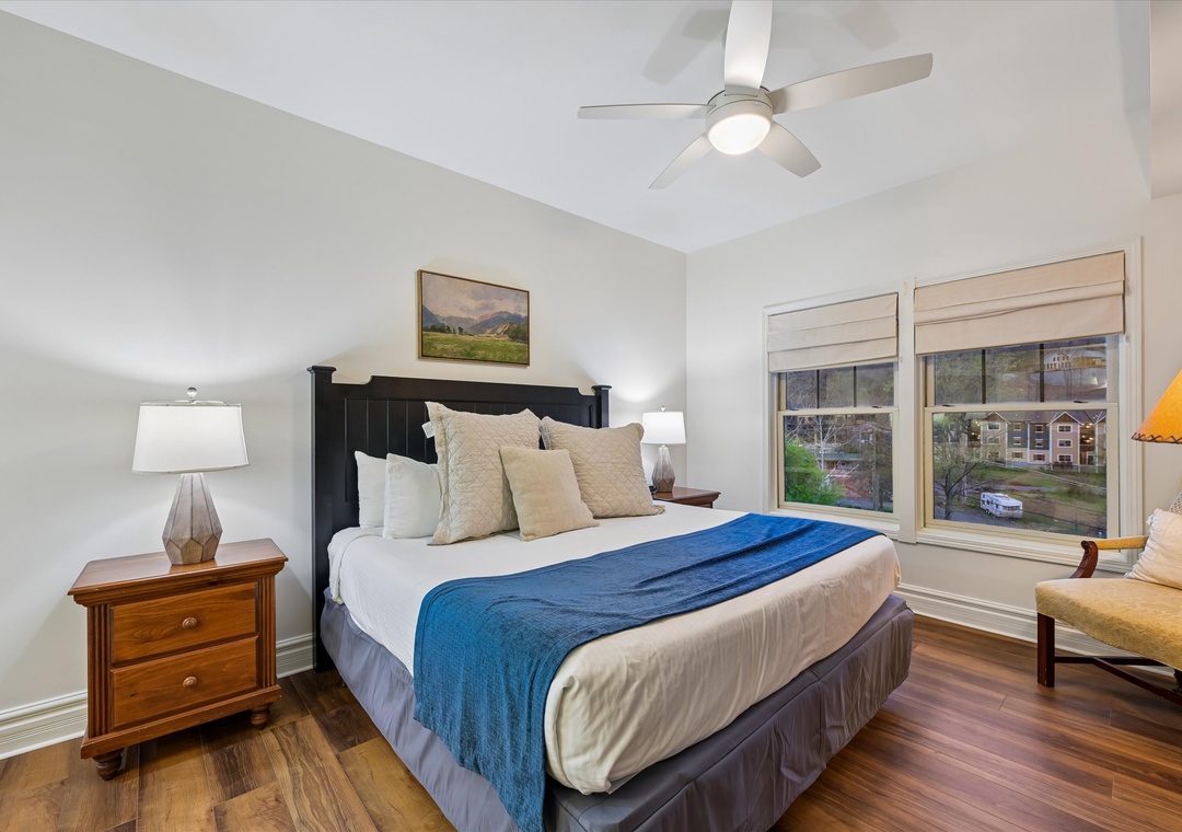 Unwind in your peaceful bedroom with luxury linens, gentle ceiling fan, and scenic mountain views through picture windows.