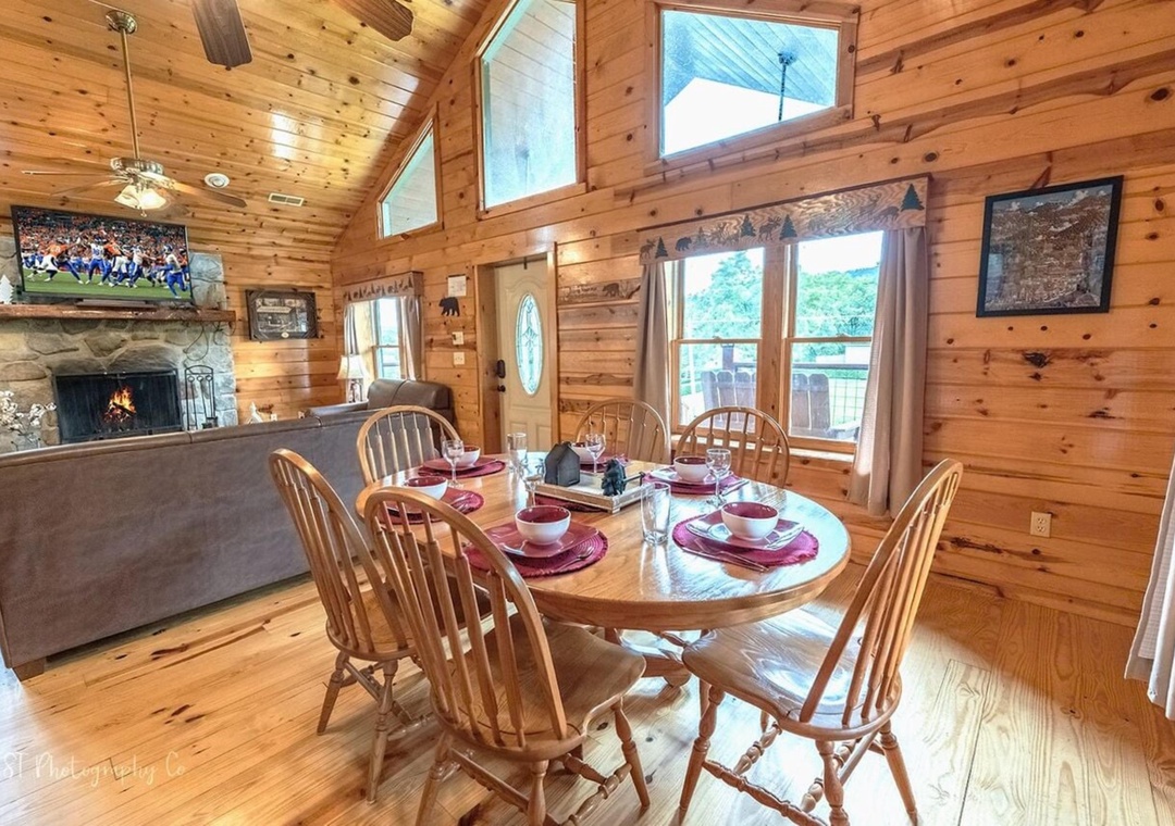 Gather around your private dining table in this warm, vaulted cabin space. Sunlight pours through tall windows, while the stone fireplace and TV create a cozy backdrop for your memorable meals together.