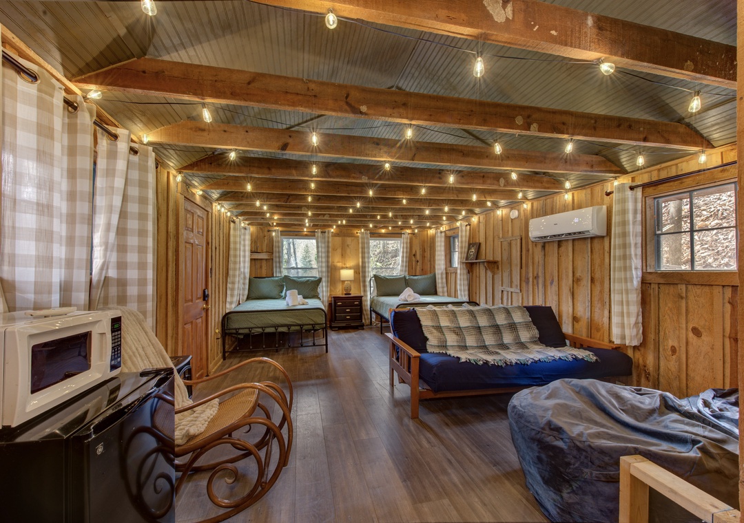 Unwind in your cozy cabin retreat with rustic wood beams, twinkling string lights, and comfortable sleeping arrangements for the whole family.