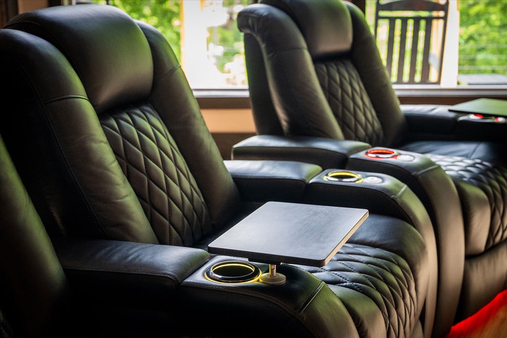 Settle into plush luxury theater seating with built-in cup holders and tray tables, perfect for your private movie nights overlooking lush garden views.