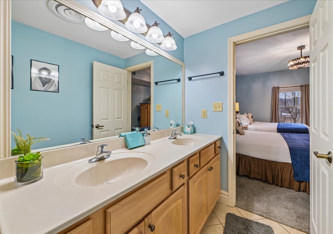 Your en-suite bathroom features dual vanities and calming blue walls, connecting seamlessly to your comfortable bedroom.