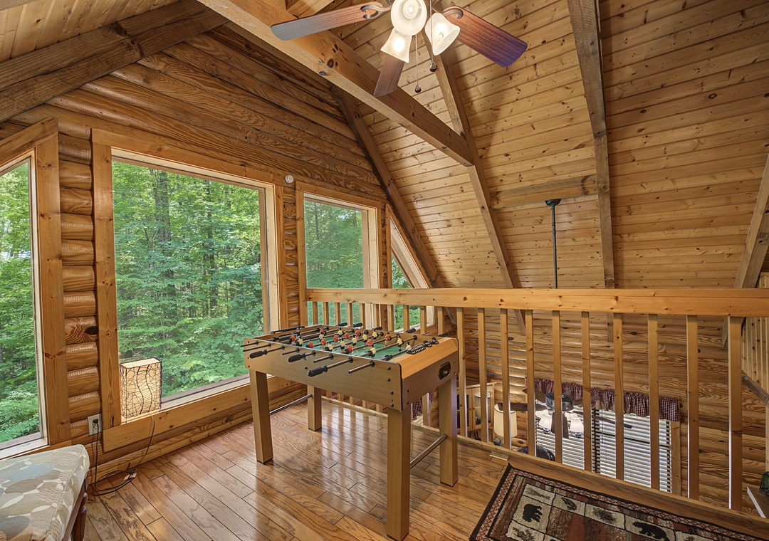 Step into your private loft game room with soaring timber ceilings, where foosball tournaments and forest views through oversized windows create the perfect mountain escape for you and your guests.