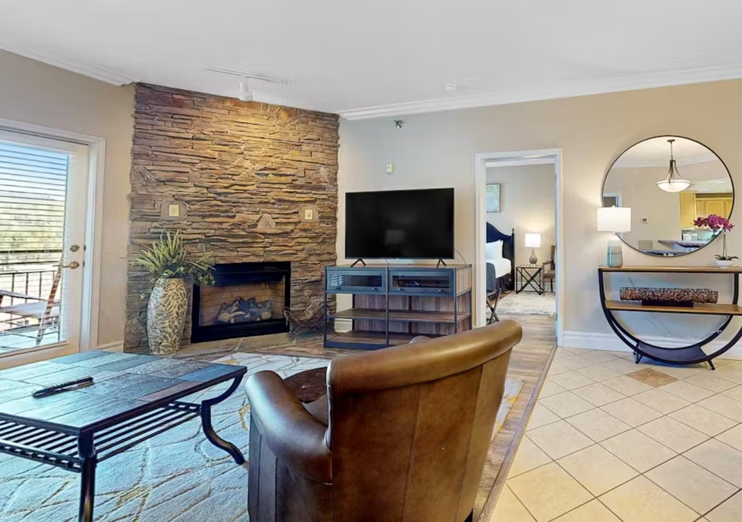 Unwind in your spacious living area featuring a cozy stone fireplace and modern entertainment center, perfect for relaxing evenings.