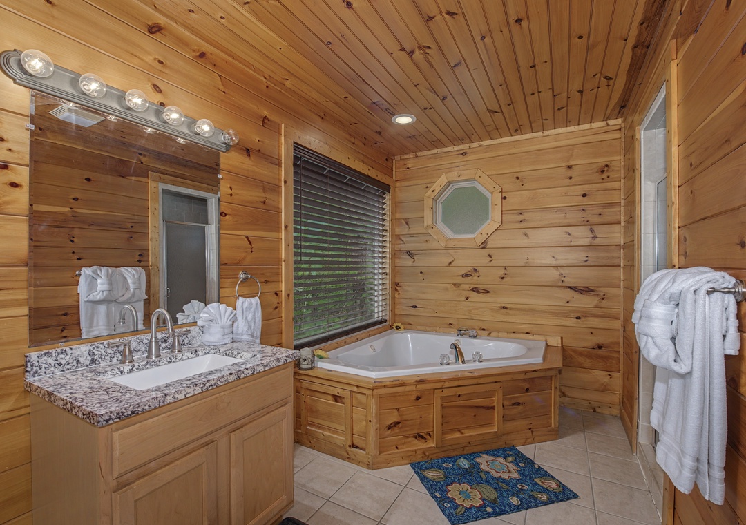 Unwind in your private bathroom with a luxurious corner tub framed by warm knotty pine. Plush towels and granite countertops make every soak feel like a spa retreat.