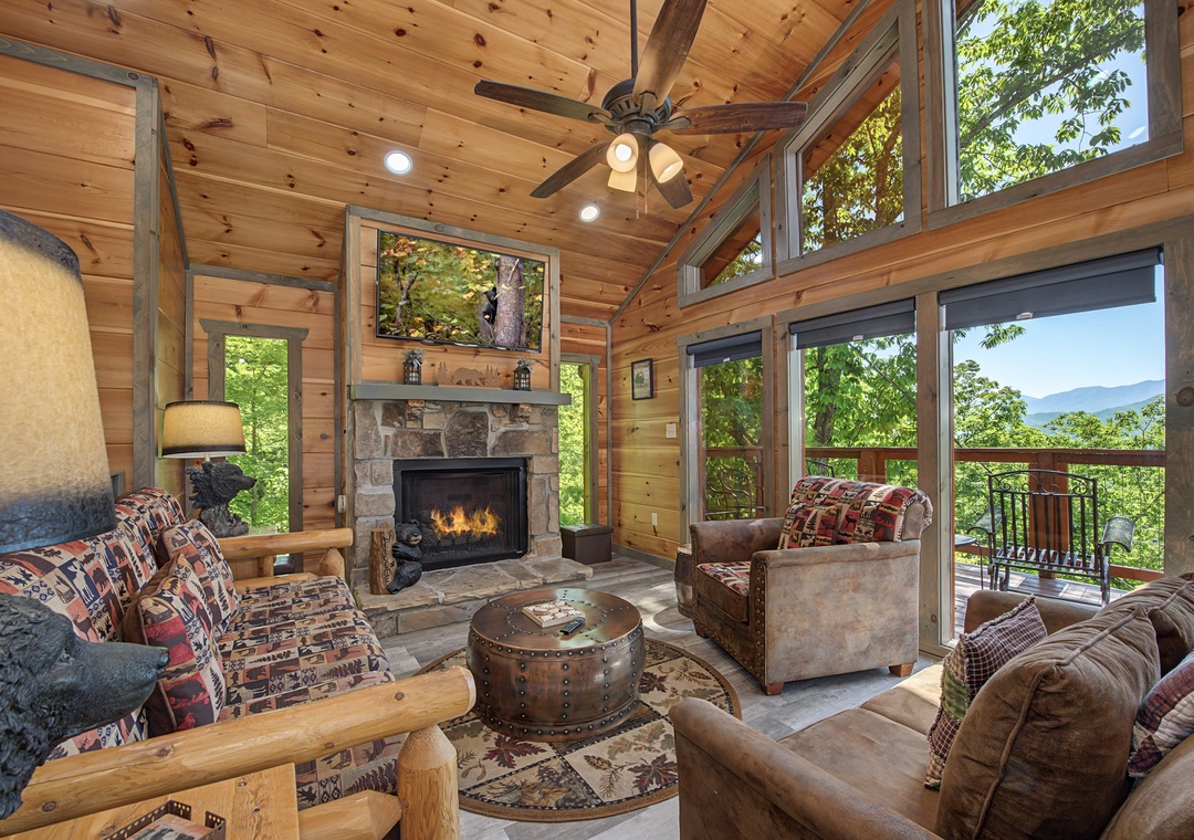 Picture yourself curled up by the stone fireplace, gazing through soaring windows at the mountains beyond. This cozy, wood-paneled retreat invites you to unwind in rustic elegance and soak in the stunning panorama.