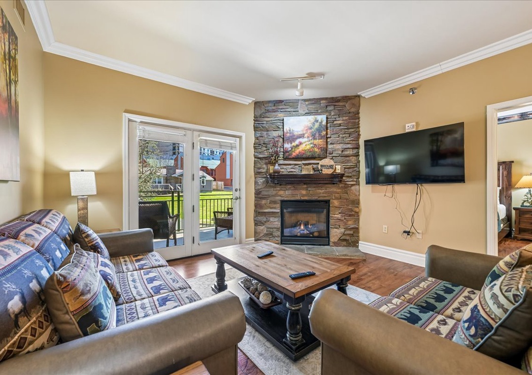 Cozy up by your stone fireplace while watching TV in this warm living room with comfortable seating and patio access.