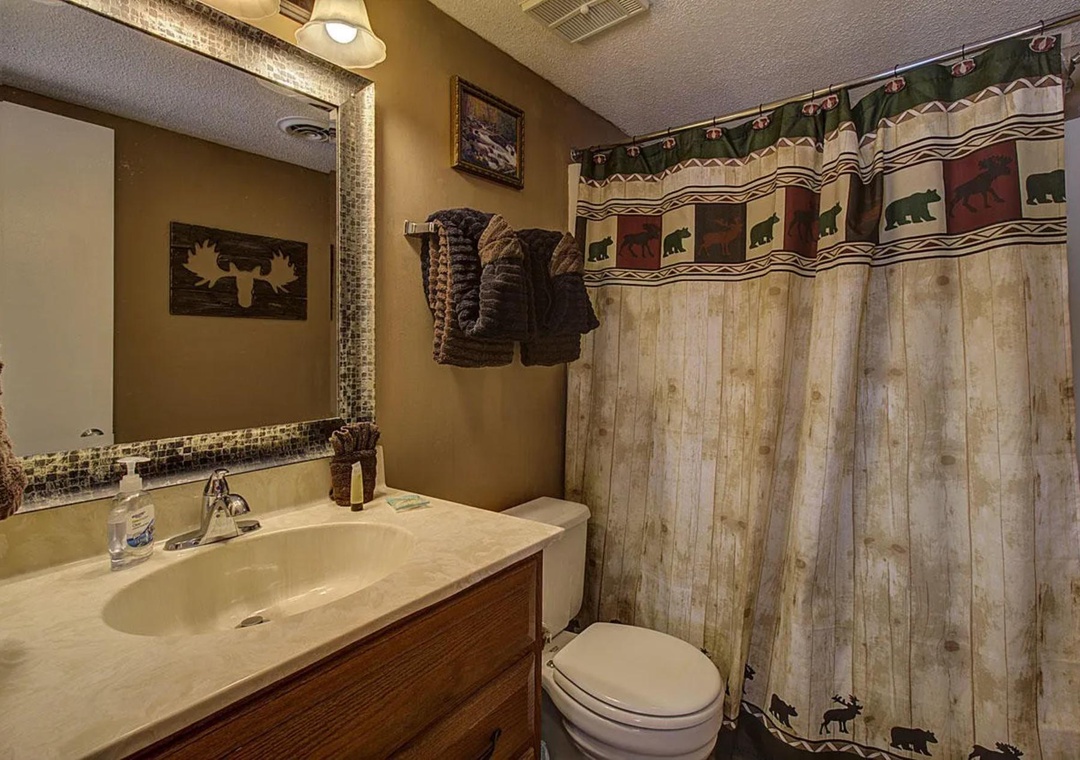 Rustic cabin bathroom with wilderness-themed shower curtain and cozy mountain lodge decor creates your perfect retreat atmosphere.
