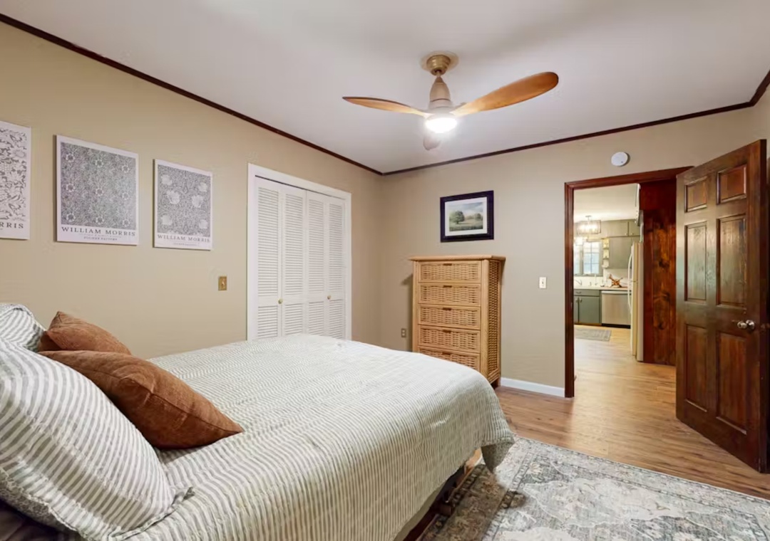 Unwind in your tranquil bedroom with rich wood trim, soft linens, and a gentle ceiling fan creating the perfect atmosphere for restful nights.