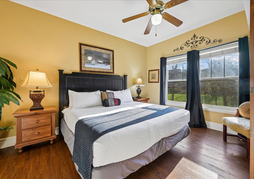 Unwind in your elegant bedroom featuring a plush king bed, warm hardwood floors, and peaceful garden views from your private window.
