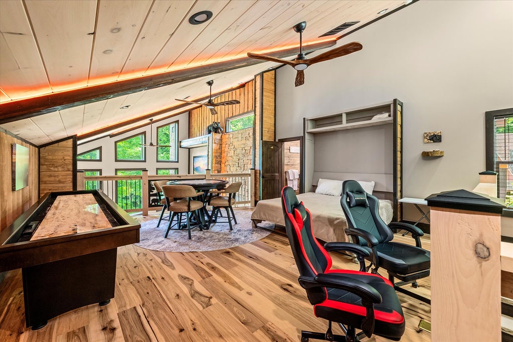 Unwind in your spacious open-concept loft with soaring ceilings, rustic wood accents, a pool table, gaming chairs, and a cozy sleeping nook—perfect for relaxation and fun.