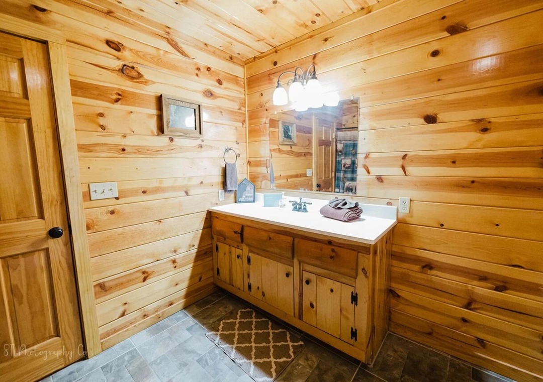 Step into your private sanctuary with warm knotty pine walls, a spacious vanity, and thoughtfully placed towels ready for your arrival.