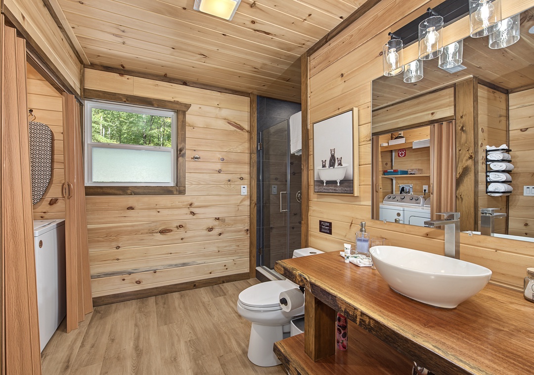 Your private bathroom blends rustic wood warmth with modern touches—a sleek vessel sink, rainfall shower, and thoughtful amenities await your arrival.