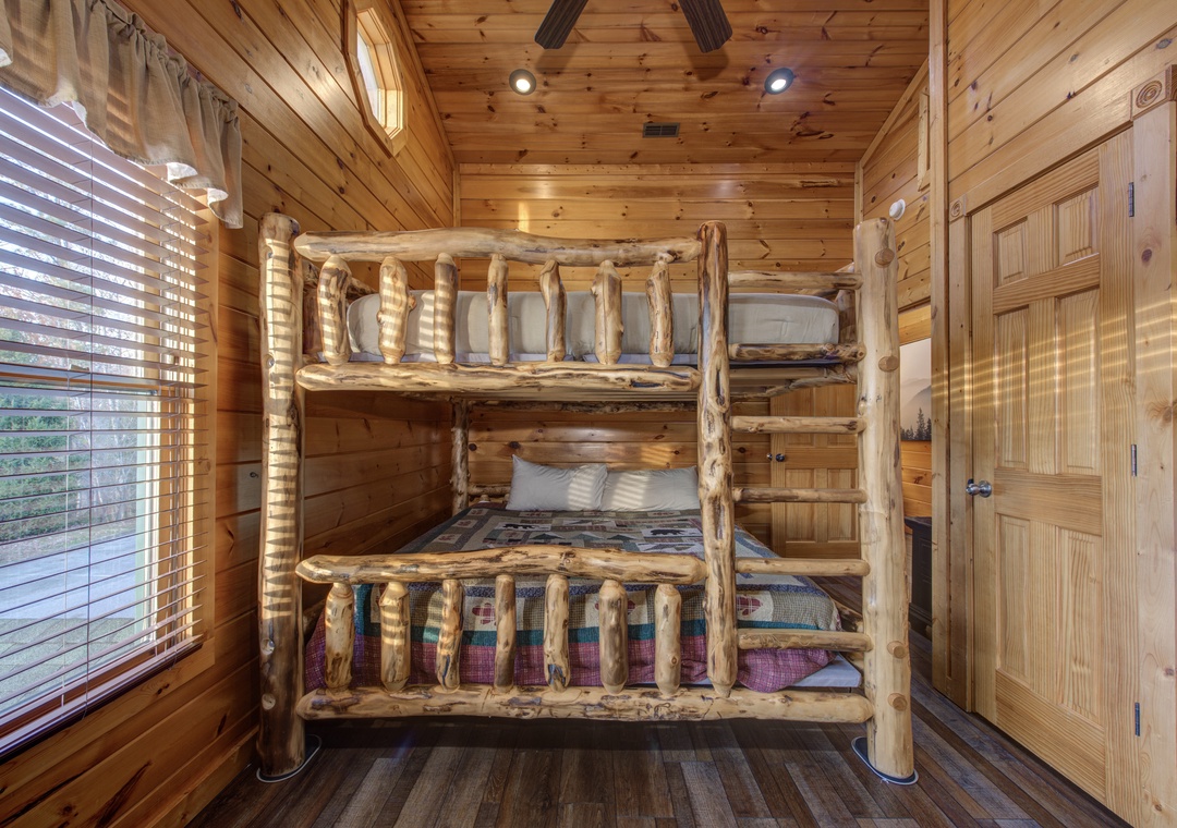Relax in this cozy bedroom featuring a handcrafted log bunk bed, warm wood-paneled walls, and soft natural light that creates a welcoming mountain retreat just for you.