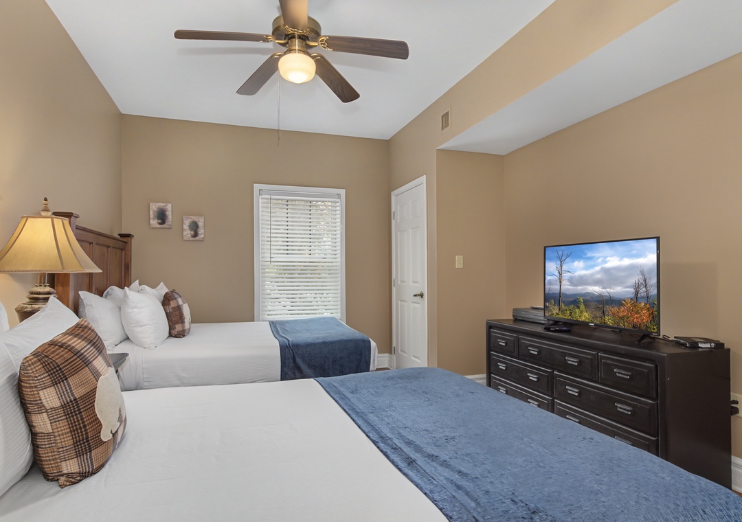 Relax in your comfortable twin bedroom with modern amenities, ceiling fan, and flat-screen TV for your entertainment.