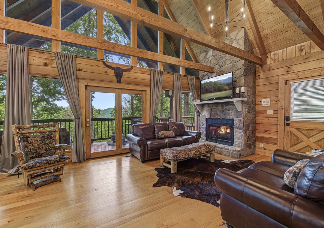 Sink into plush leather sofas by the warm glow of your stone fireplace, where vaulted wood-beam ceilings and floor-to-ceiling windows frame breathtaking mountain views. Your peaceful retreat awaits with rustic charm and modern comfort.