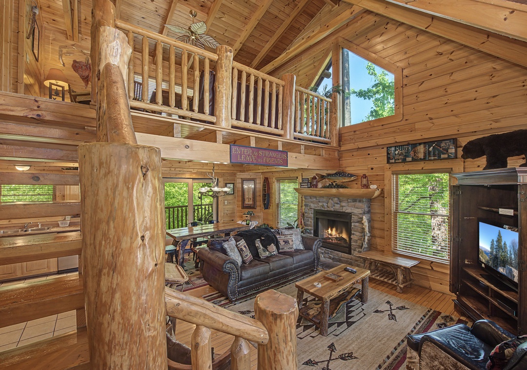 Relax in this stunning log cabin living room where rustic charm meets modern comfort, with soaring ceilings and a cozy fireplace.