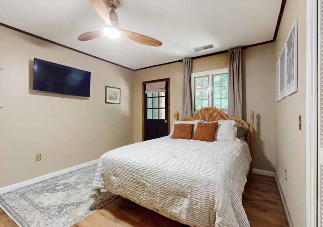 Drift into peaceful dreams in your cozy bedroom, featuring a plush queen bed, ceiling fan, and warm natural light streaming through charming windows.